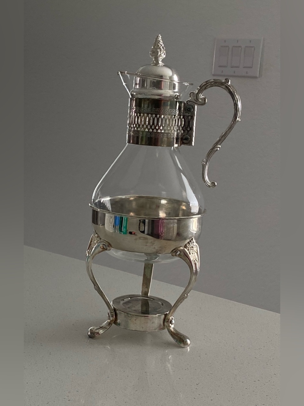 Silver vintage glass jug with stand, embossed floral design.